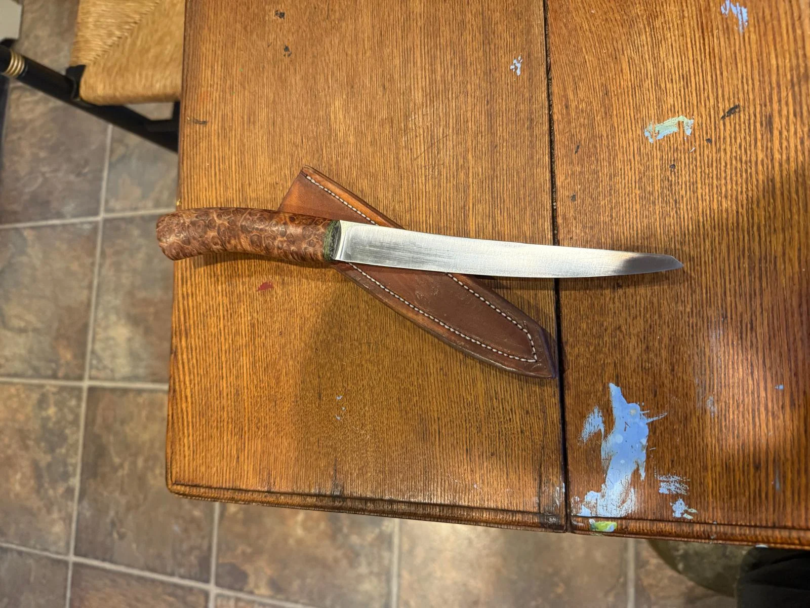 Though I have had many through the years, this has been far and away my favorite. Very light in the hand, I keep it in the kitchen when I have only a few fish to clean and don’t want to break out the electric knife. Also great for slicing fruit, tomatoes, etc. Made from Swedish Sandvik 14C28N Steel. Overall Blade length is 7”: Cutting surface 6 1/2”: Tanto style point. Handle Material is stabilized resin-impregnated Spalted Maple. Comes with a heavy leather drawer sheath.